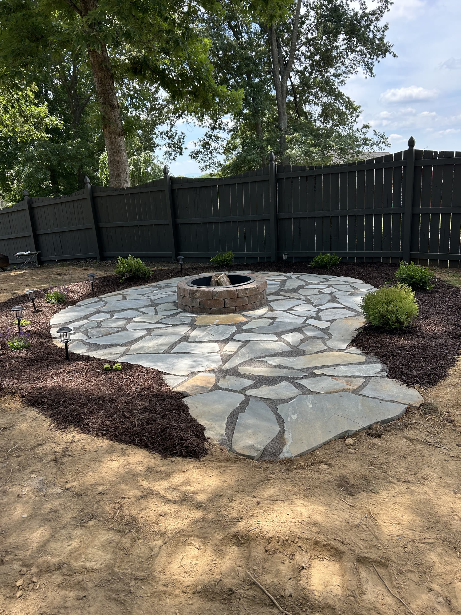 Flagstone patio and stone fire pit with mulched plantings