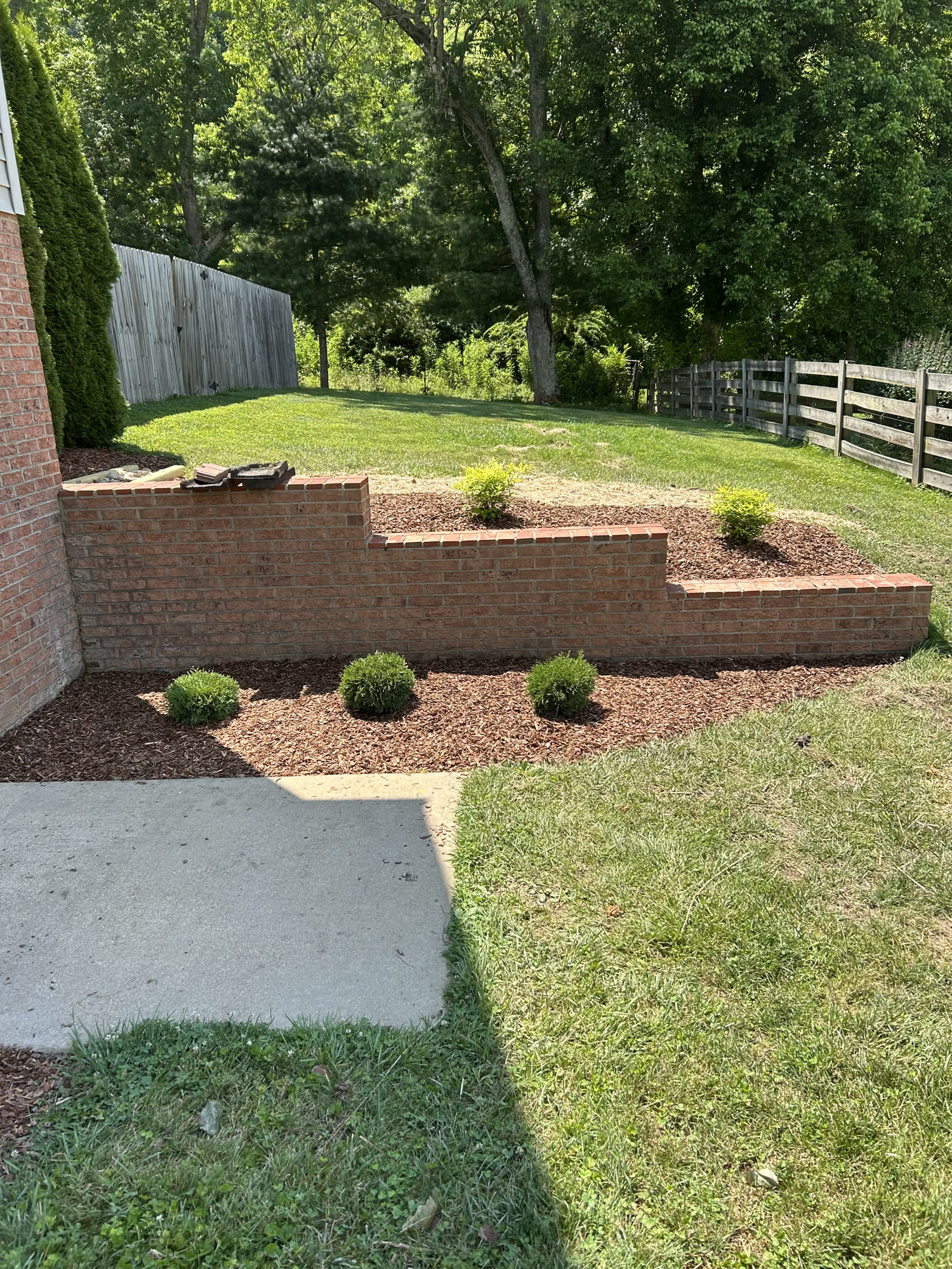 Stepped brick retaining wall with fresh mulch and shrubs